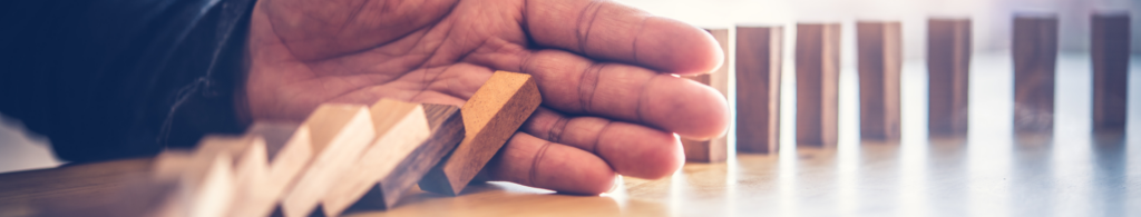 Image of risk management concept - hand stopping dominoes from falling